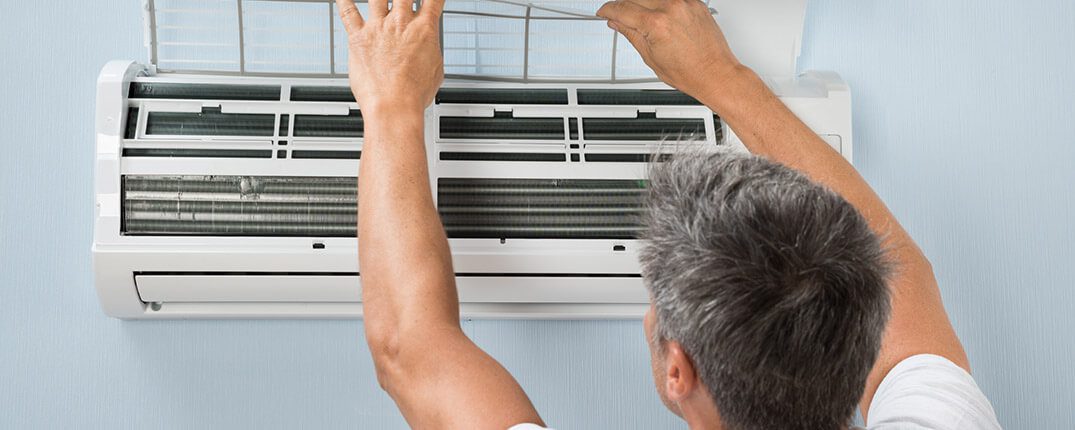 DunRite Heating & Air Inc. - Man cleaning air conditioning system