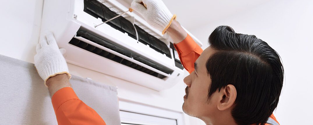 DunRite Heating & Air Inc. - male technician repairing air conditioner
