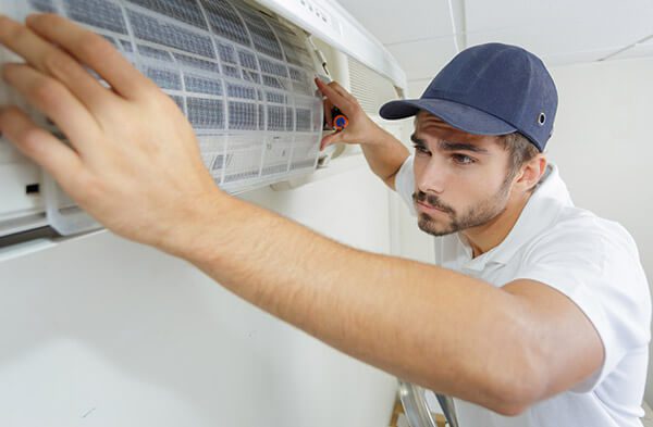 DunRite Heating & Air Inc. -male technician repairing air conditioner
