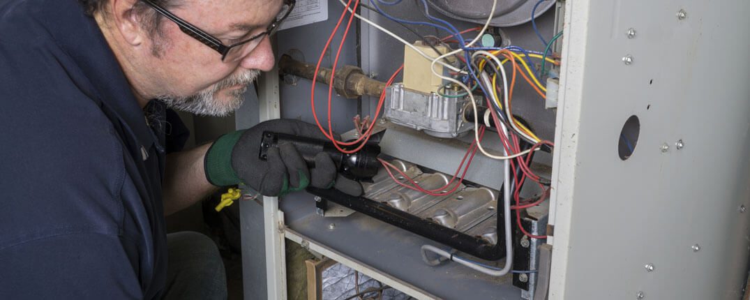 DunRite Heating & Air Inc. - technician looking over a gas furnace
